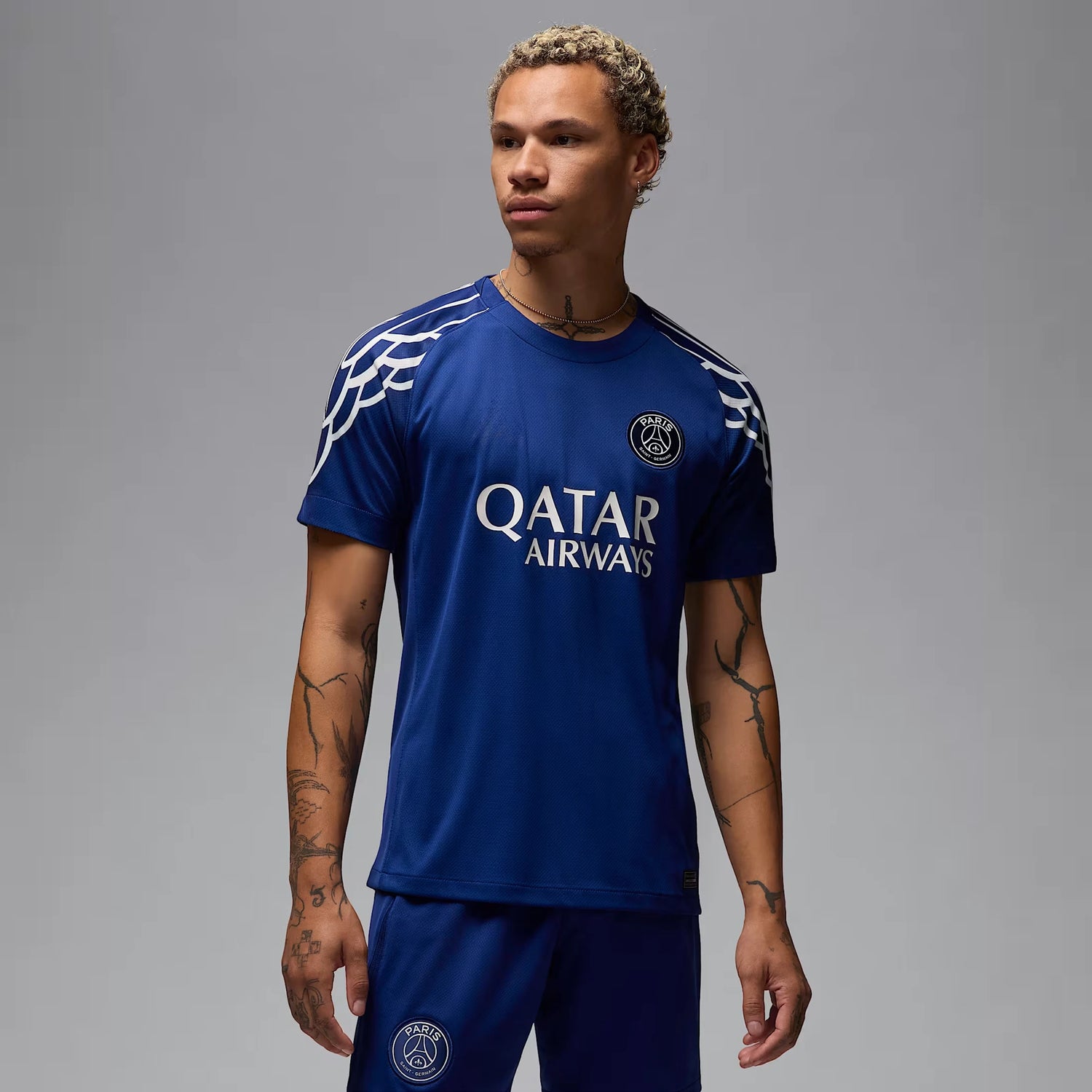 En man bär Paris Saint-Germains fjärdetröja för säsongen 2024/25 i marinblå färg, med Qatar Airways som sponsor och Jordan-logotyp på bröstet.